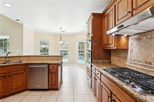 89 Catalpa Trce, Covington, LA 70433 - kitchen featuring stainless steel appliances, under cabinet range hood, brown cabinets, decorative backsplash, and light stone countertops