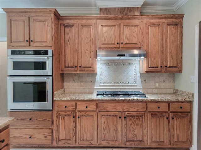 89 Catalpa Trce, Covington, LA 70433 - kitchen featuring under cabinet range hood, appliances with stainless steel finishes, tasteful backsplash, light stone countertops, and ornamental molding
