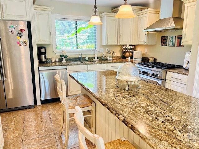 14 Riverbend Ln, Covington, LA 70433 - kitchen featuring stainless steel appliances, wall chimney exhaust hood, a breakfast bar area, dark stone counters, and decorative light fixtures