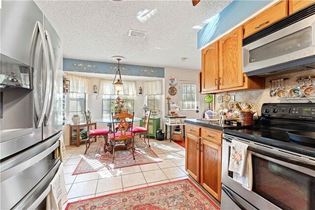 101 E Queensbury Dr, Slidell, LA 70461 - kitchen featuring stainless steel appliances, light tile patterned floors, decorative backsplash, decorative light fixtures, and dark countertops