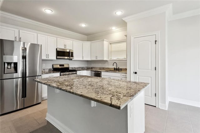 386 Knollwood Ln, Slidell, LA 70458 - kitchen featuring appliances with stainless steel finishes, white cabinets, light stone countertops, a center island, and ornamental molding