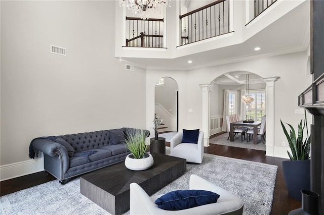 172 River Oaks Dr, La Place, LA 70068 - living room with decorative columns, arched walkways, a chandelier, wood finished floors, and stairs