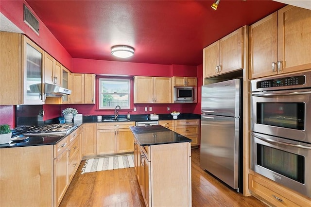 5237 Meadowdale St, Metairie, LA 70006 - kitchen featuring stainless steel appliances, light wood-style flooring, dark countertops, and under cabinet range hood
