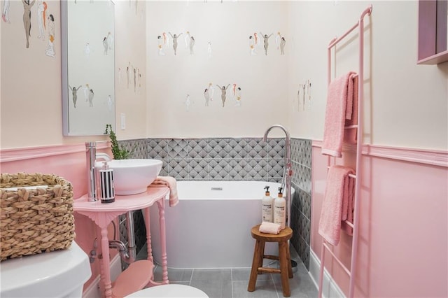 1932 Lapeyrouse St, New Orleans, LA 70116 - bathroom with a tub to relax in, tile patterned flooring, a wainscoted wall, and tile walls