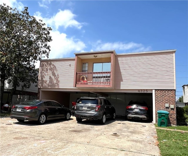 4325 Loire Dr, Kenner, LA 70065 - view of front of home featuring concrete driveway, a balcony, a carport, and brick siding