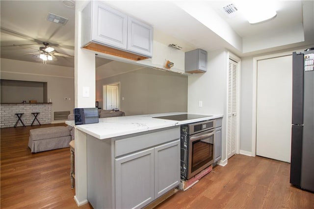2137 Carmel Valley Dr, La Place, LA 70068 - kitchen with black appliances, light wood finished floors, a ceiling fan, and light stone countertops
