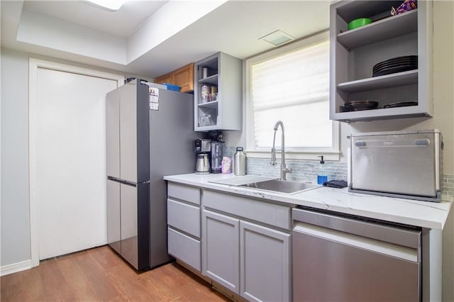 2137 Carmel Valley Dr, La Place, LA 70068 - kitchen featuring stainless steel appliances, open shelves, light wood-type flooring, and backsplash