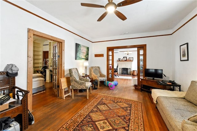 1815 S White St, New Orleans, LA 70125 - living room featuring a fireplace with raised hearth, a ceiling fan, wood finished floors, and crown molding