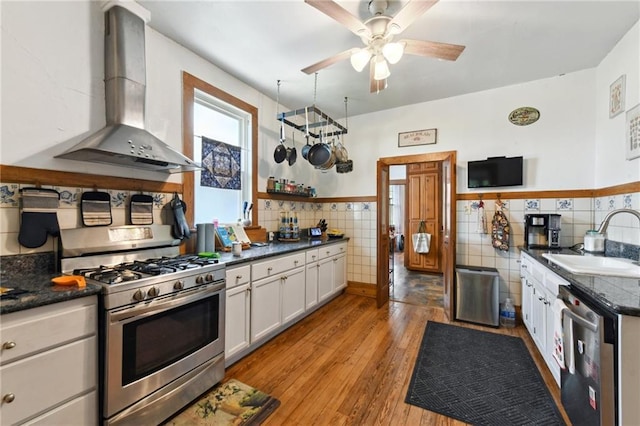 1815 S White St, New Orleans, LA 70125 - kitchen featuring appliances with stainless steel finishes, wall chimney exhaust hood, tile walls, dark countertops, and white cabinets