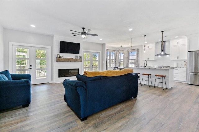 4320 Alba Rd, New Orleans, LA 70129 - living room featuring french doors, recessed lighting, light wood-type flooring, ceiling fan, and a fireplace