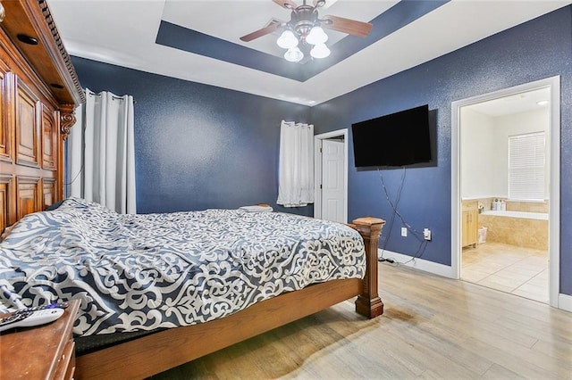4320 Alba Rd, New Orleans, LA 70129 - bedroom with light wood-style flooring, ensuite bath, a raised ceiling, and a ceiling fan