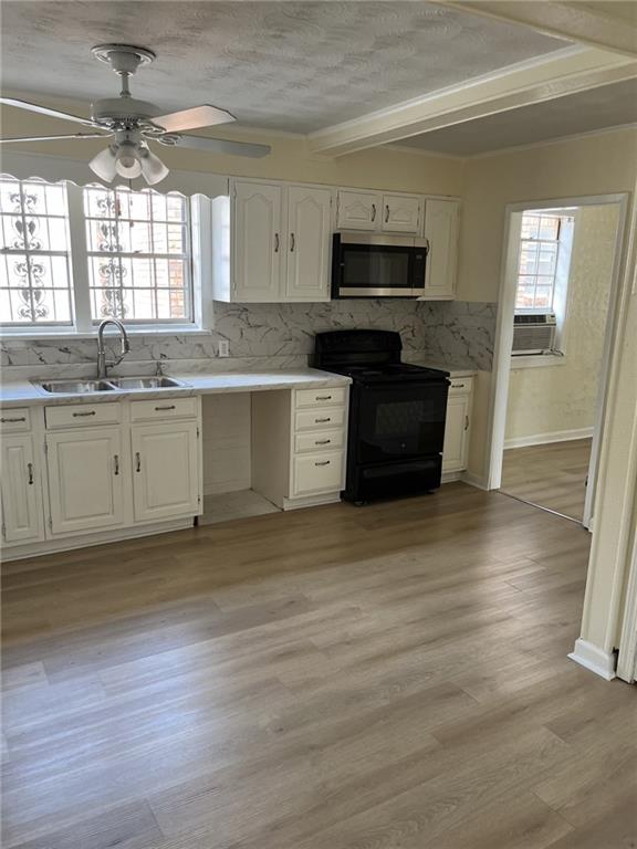 1615 Pratt St, Gretna, LA 70053 - kitchen with black range with electric cooktop, stainless steel microwave, tasteful backsplash, plenty of natural light, and beamed ceiling