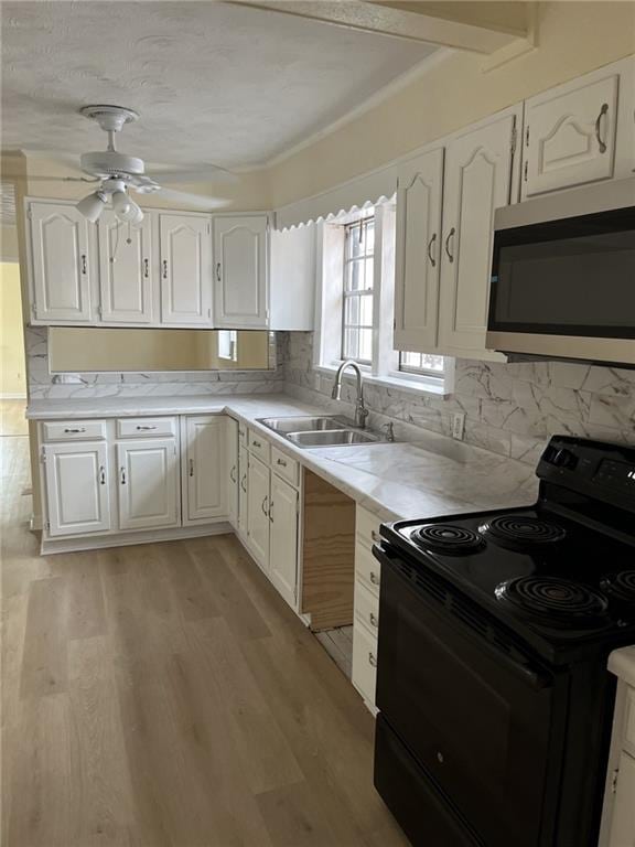 1615 Pratt St, Gretna, LA 70053 - kitchen with black range with electric cooktop, stainless steel microwave, white cabinetry, and light countertops