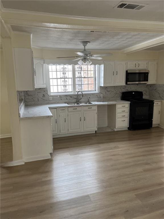 1615 Pratt St, Gretna, LA 70053 - kitchen with stainless steel microwave, electric range, decorative backsplash, white cabinets, and crown molding