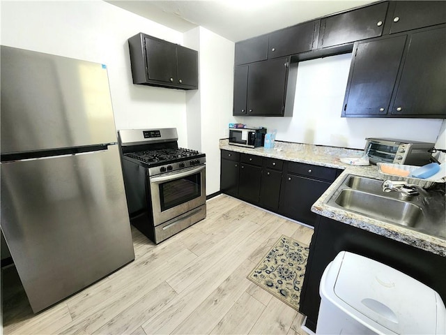 106 Treuil Ln, Belle Chasse, LA 70037 - kitchen with stainless steel appliances, dark cabinetry, light wood-style floors, and light countertops