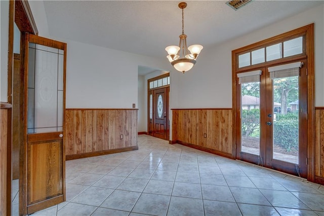 119 Gondrella Dr, Belle Chasse, LA 70037 - unfurnished room featuring a wainscoted wall, healthy amount of natural light, wood walls, french doors, and a chandelier