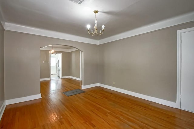 157 Gruner Rd, Metairie, LA 70001 - empty room with arched walkways, a chandelier, wood finished floors, and a raised ceiling