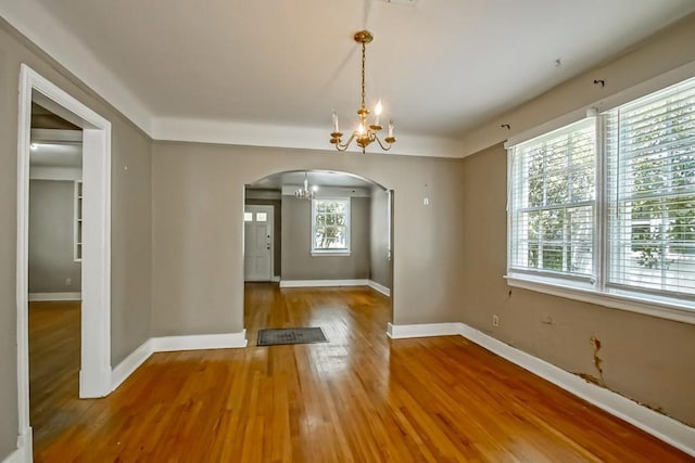 157 Gruner Rd, Metairie, LA 70001 - unfurnished dining area featuring arched walkways, a chandelier, healthy amount of natural light, and wood finished floors