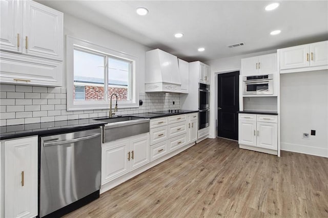 57 Driftwood Blvd, Kenner, LA 70065 - kitchen with appliances with stainless steel finishes, dark countertops, premium range hood, light wood-style flooring, and recessed lighting