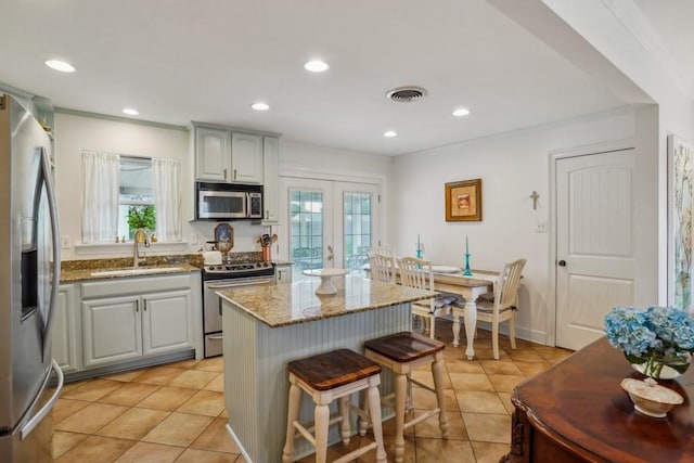 4320 Academy Dr, Metairie, LA 70003 - kitchen with appliances with stainless steel finishes, french doors, light stone counters, a center island, and a breakfast bar area