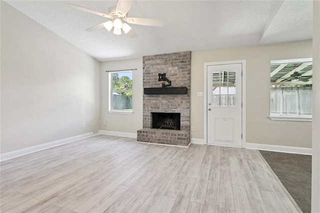 128 Hollow Rock Ct, Slidell, LA 70461 - unfurnished living room with ceiling fan, wood finished floors, a brick fireplace, and a textured ceiling