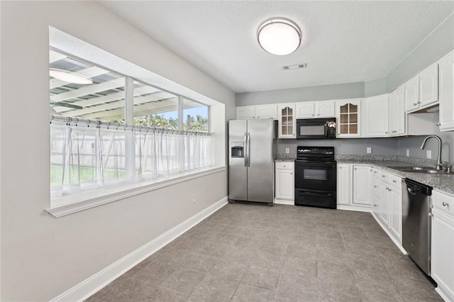 128 Hollow Rock Ct, Slidell, LA 70461 - kitchen with black appliances, glass insert cabinets, light stone counters, white cabinets, and a textured ceiling