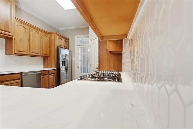 319 Red Maple Dr, Mandeville, LA 70448 - kitchen with stainless steel appliances, light countertops, brown cabinetry, tasteful backsplash, and crown molding