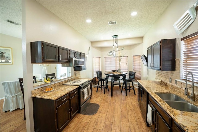 157 Barnes Ct, Gretna, LA 70056 - kitchen featuring stainless steel appliances, a textured ceiling, light wood finished floors, dark brown cabinets, and pendant lighting