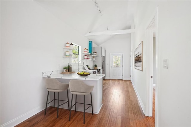 1431 Port St, New Orleans, LA 70117 - kitchen with a kitchen breakfast bar, a peninsula, light countertops, hardwood / wood-style floors, and high vaulted ceiling