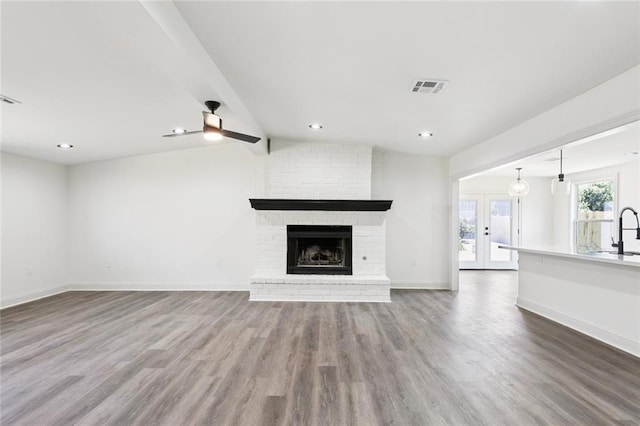 12 Fairlane Dr, Metairie, LA 70003 - unfurnished living room featuring wood finished floors, ceiling fan, a fireplace, recessed lighting, and french doors