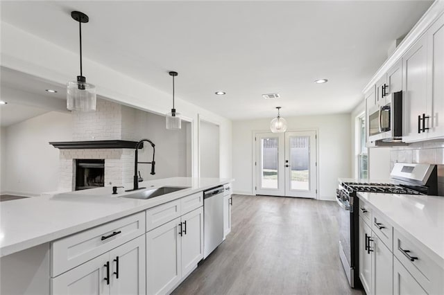 12 Fairlane Dr, Metairie, LA 70003 - kitchen with appliances with stainless steel finishes, french doors, decorative light fixtures, white cabinetry, and light countertops