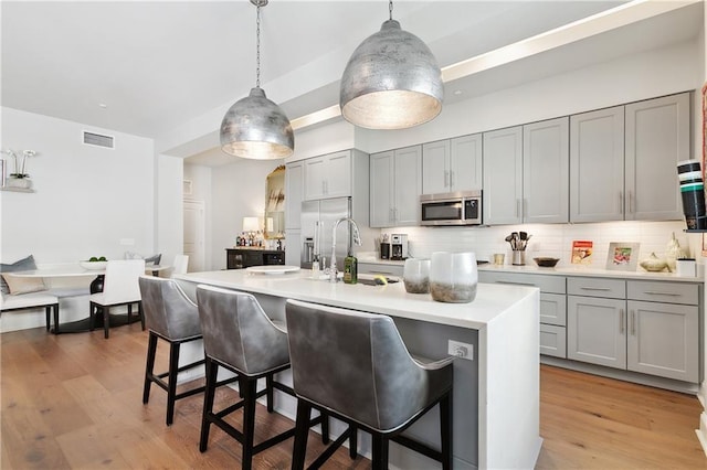 731 St Charles Ave Unit 310, New Orleans, LA 70130 - kitchen featuring stainless steel appliances, gray cabinetry, a breakfast bar, decorative backsplash, and light countertops