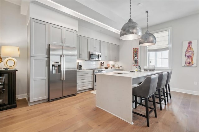 731 St Charles Ave Unit 310, New Orleans, LA 70130 - kitchen featuring stainless steel appliances, light wood finished floors, an island with sink, and gray cabinetry