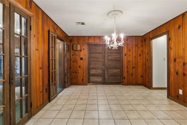 202 Amelia St, Destrehan, LA 70047 - unfurnished dining area with a chandelier, wood walls, and light tile patterned floors
