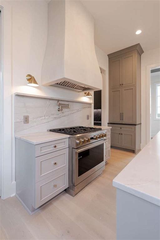 209 Avenue E Ave E, Metairie, LA 70005 - kitchen with high end range, premium range hood, backsplash, light wood finished floors, and recessed lighting