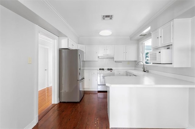 53 Beverly Garden Dr, Metairie, LA 70001 - kitchen with appliances with stainless steel finishes, under cabinet range hood, a peninsula, dark wood-style floors, and white cabinetry
