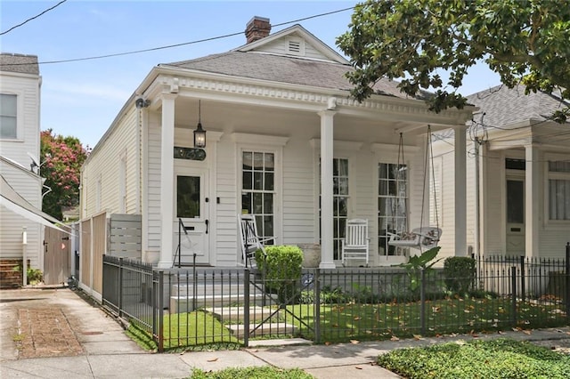 1123 Cadiz St, New Orleans, LA 70115 - shotgun-style home with a porch, a gate, a fenced front yard, a chimney, and a shingled roof