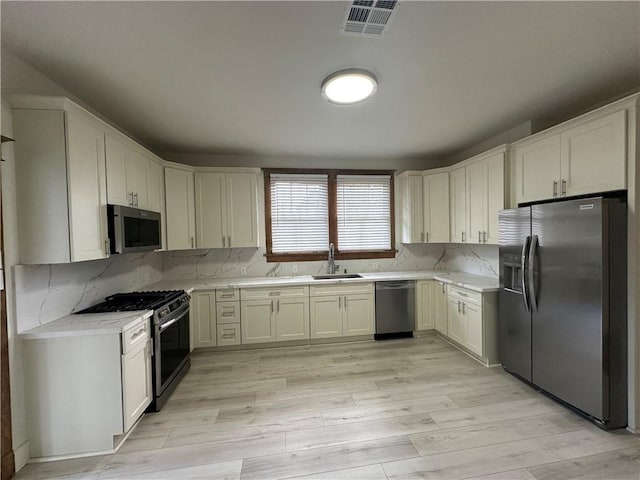 1401 Jefferson St, Gretna, LA 70053 - kitchen with appliances with stainless steel finishes, light wood-type flooring, backsplash, and light stone counters