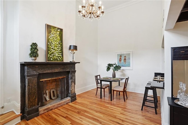 1303 Burgundy St Unit 3, New Orleans, LA 70116 - dining area with wood finished floors, a fireplace with raised hearth, crown molding, a chandelier, and a high ceiling