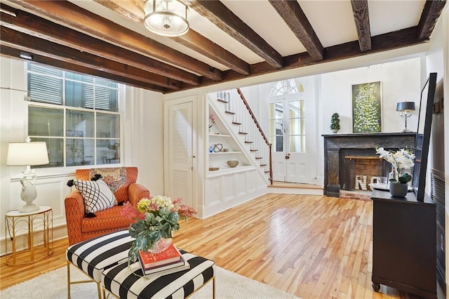 1303 Burgundy St Unit 3, New Orleans, LA 70116 - living area with stairway, beam ceiling, wood finished floors, and a fireplace with raised hearth