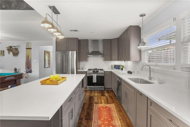 159 Valerie St, River Ridge, LA 70123 - kitchen with appliances with stainless steel finishes, wall chimney range hood, dark wood-style flooring, light countertops, and pendant lighting