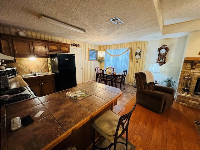 6655 Dalark Dr, Baton Rouge, LA 70812 - kitchen with a textured ceiling, freestanding refrigerator, stainless steel microwave, a peninsula, and a breakfast bar