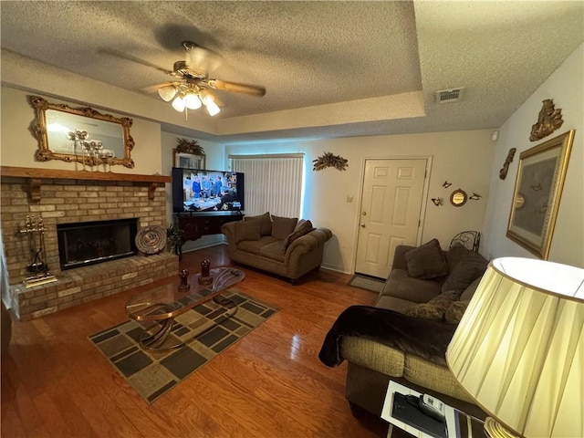 6655 Dalark Dr, Baton Rouge, LA 70812 - living room with a textured ceiling, wood finished floors, a ceiling fan, a tray ceiling, and a fireplace