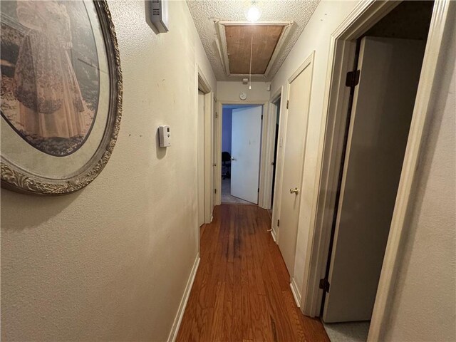 6655 Dalark Dr, Baton Rouge, LA 70812 - hall with attic access, wood finished floors, and a textured ceiling