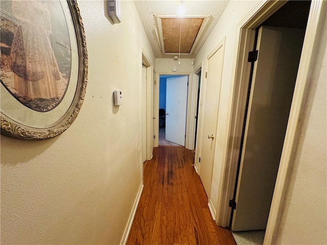 6655 Dalark Dr, Baton Rouge, LA 70812 - hallway featuring attic access, wood finished floors, and a textured ceiling