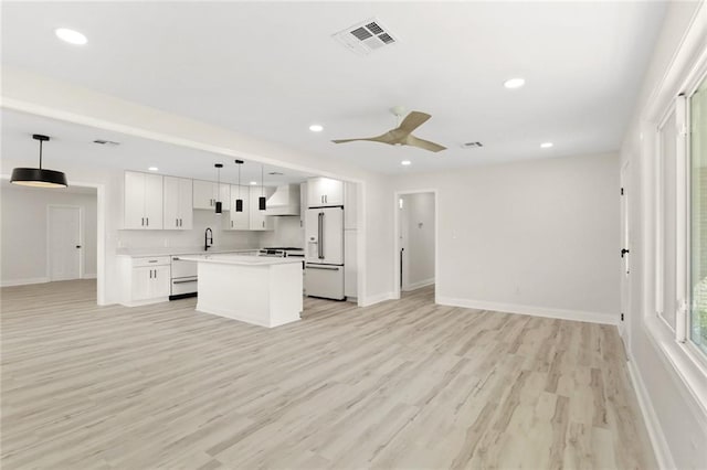 40 Holly Dr, Gretna, LA 70053 - kitchen featuring white refrigerator with ice dispenser, open floor plan, wall chimney exhaust hood, a kitchen island, and white cabinets