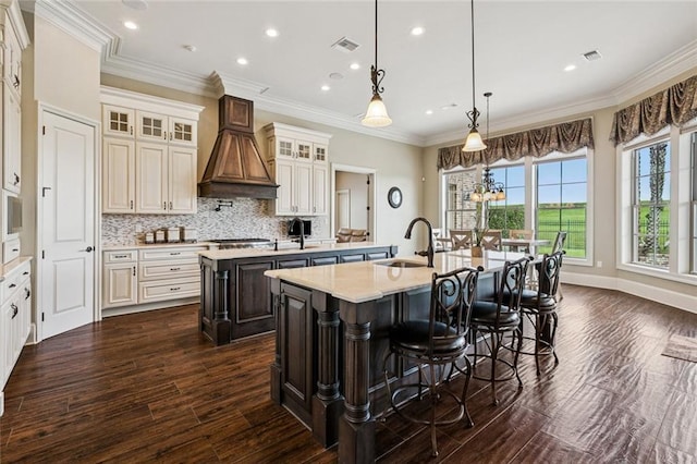 24 Royal Palm Dr, Kenner, LA 70065 - kitchen featuring a kitchen island with sink, dark wood-type flooring, light countertops, decorative backsplash, and glass insert cabinets
