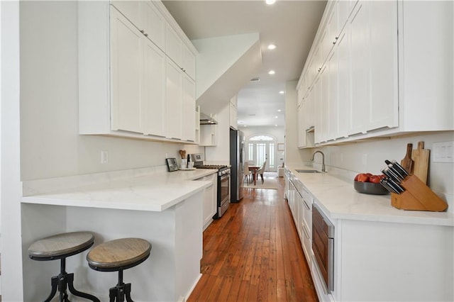 20810 S Scott St, New Orleans, LA 70119 - kitchen with appliances with stainless steel finishes, recessed lighting, white cabinets, a breakfast bar area, and dark wood-style flooring
