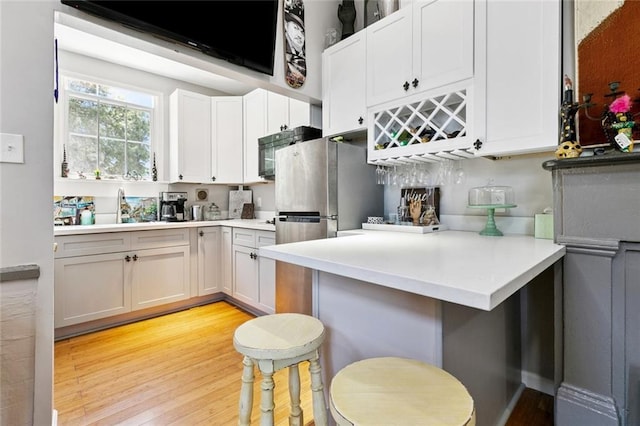 922 Elysian Fields Ave Unit B, New Orleans, LA 70117 - kitchen featuring light wood-type flooring, light countertops, white cabinets, and a breakfast bar area