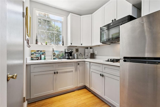 922 Elysian Fields Ave Unit B, New Orleans, LA 70117 - kitchen with freestanding refrigerator, light wood-style floors, light countertops, and black microwave